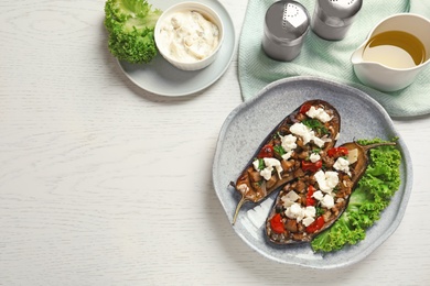 Flat lay composition with plate of stuffed eggplants and space for text on light table