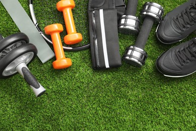 Photo of Different sports equipment on green grass, flat lay. Space for text