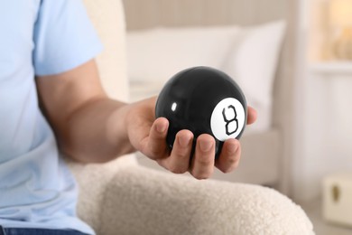 Photo of Man holding magic eight ball indoors, closeup