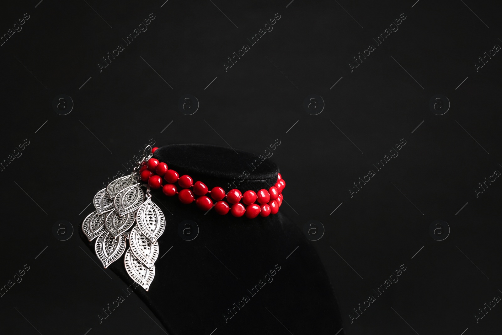 Photo of Stylish jewelry on stand against black background, space for text