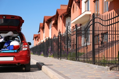 Photo of Family car with open trunk full of luggage in city. Space for text