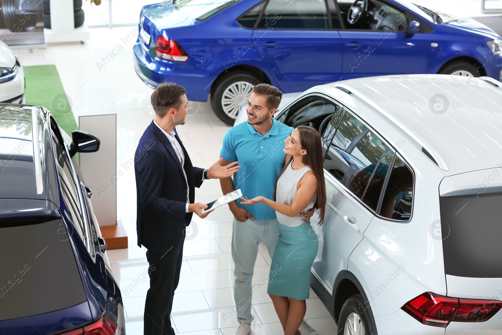 Photo of Salesman consulting young couple in car salon