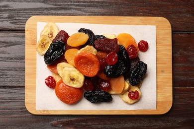 Photo of Mix of delicious dried fruits on wooden table, top view