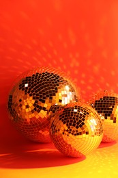 Photo of Many shiny disco balls near color wall, toned in orange