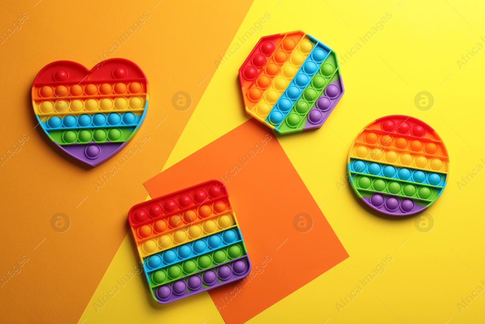 Photo of Many different rainbow pop it fidget toys on color background, flat lay