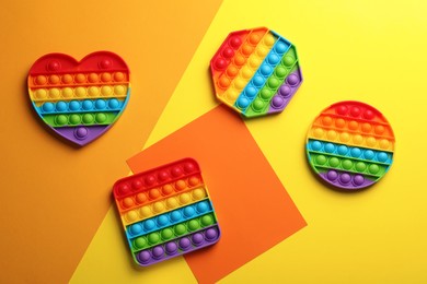 Photo of Many different rainbow pop it fidget toys on color background, flat lay