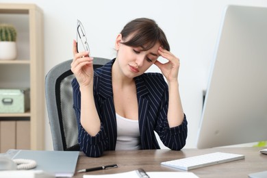 Overwhelmed office worker sitting at table with computer indoors