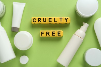 Photo of Flat lay composition with words Cruelty Free and different cosmetic products not tested on animals against green background