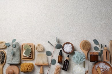 Flat lay composition with different spa products and eucalyptus branches on light grey textured table. Space for text