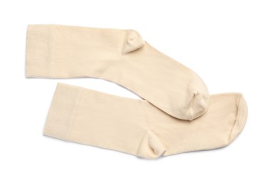 Photo of Pair of beige socks on white background, top view
