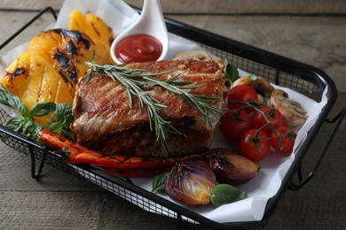 Delicious grilled meat and vegetables served with sauce on wooden table, closeup