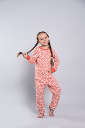 Photo of Cute girl in pajamas with floral pattern on light grey background