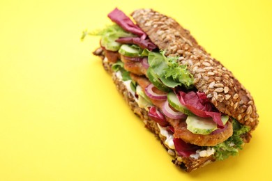 Photo of Delicious sandwich with schnitzel on yellow background, closeup. Space for text