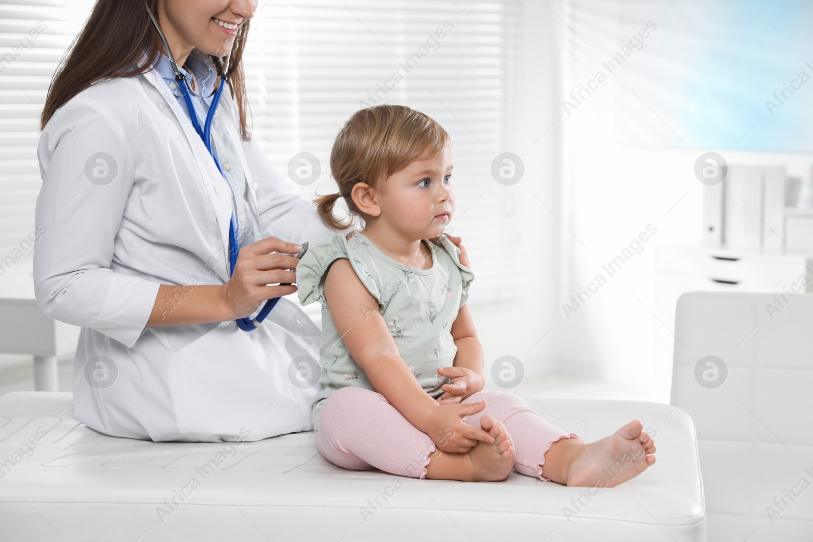 Photo of Pediatrician examining baby with stethoscope in clinic