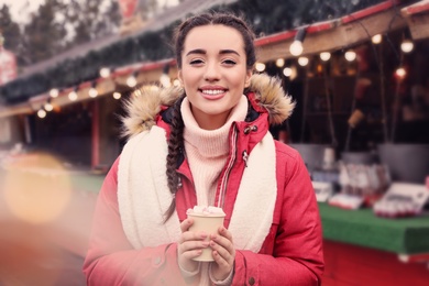 Photo of Young woman with hot drink at Christmas fair