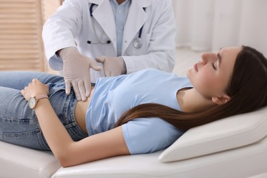 Photo of Gastroenterologist examining patient with stomach pain on couch in clinic, closeup