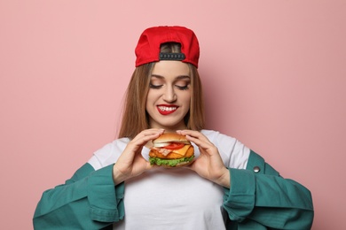 Photo of Pretty woman with tasty burger on color background