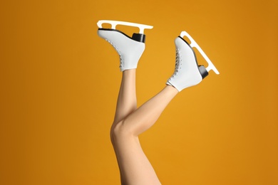 Woman in elegant white ice skates on yellow background, closeup of legs