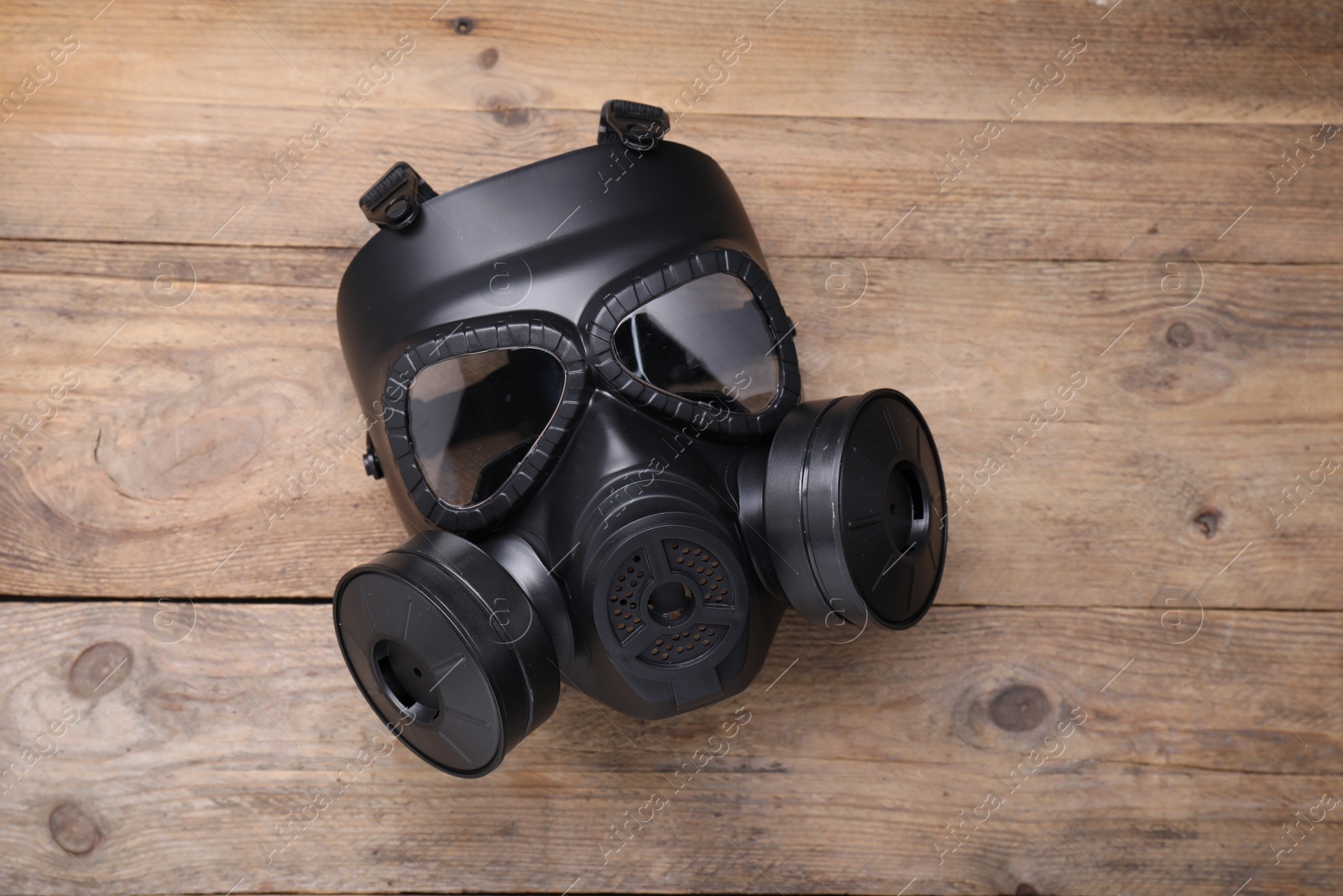 Photo of One gas mask on wooden background, top view