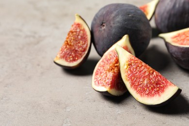 Whole and cut ripe figs on light grey textured table, closeup. Space for text