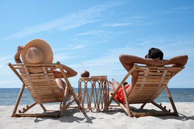 Photo of Couple resting in wooden sunbeds on tropical beach