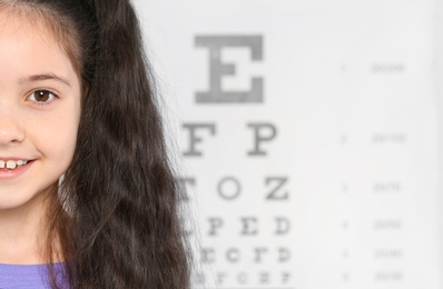 Cute little girl visiting children's doctor, closeup view with space for text. Eye examination