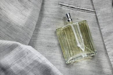 Photo of Luxury men's perfume in bottle on grey jacket, top view. Space for text