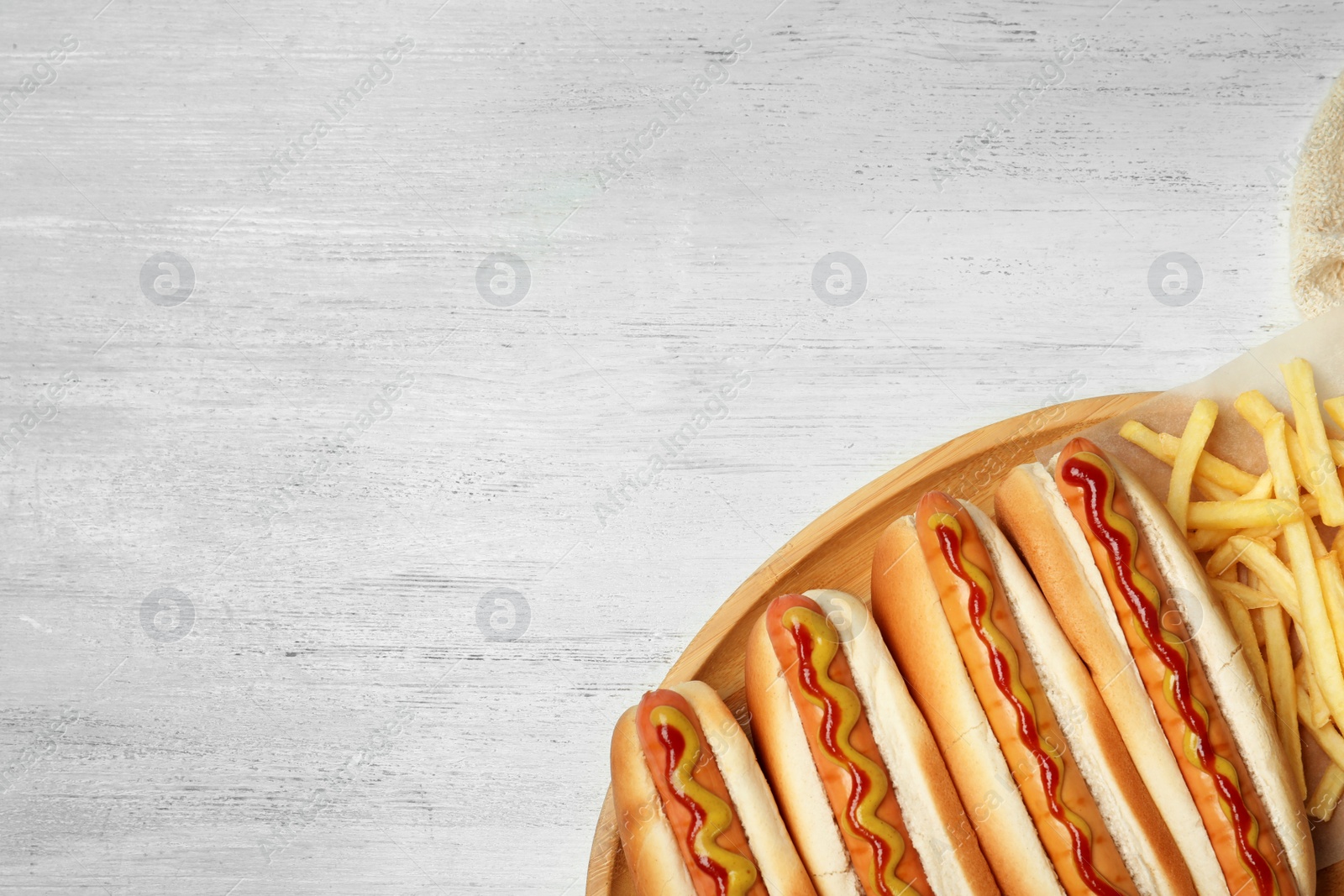 Photo of Hot dogs and french fries on wooden table, top view. Space for text