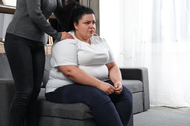 Woman comforting her depressed overweight friend at home