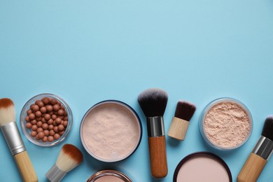 Photo of Different face powders and makeup brushes on light blue background, flat lay. Space for text