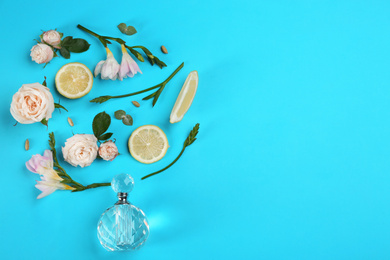 Beautiful flat lay composition with bottle of perfume, lemon and flowers on blue background. Space for text
