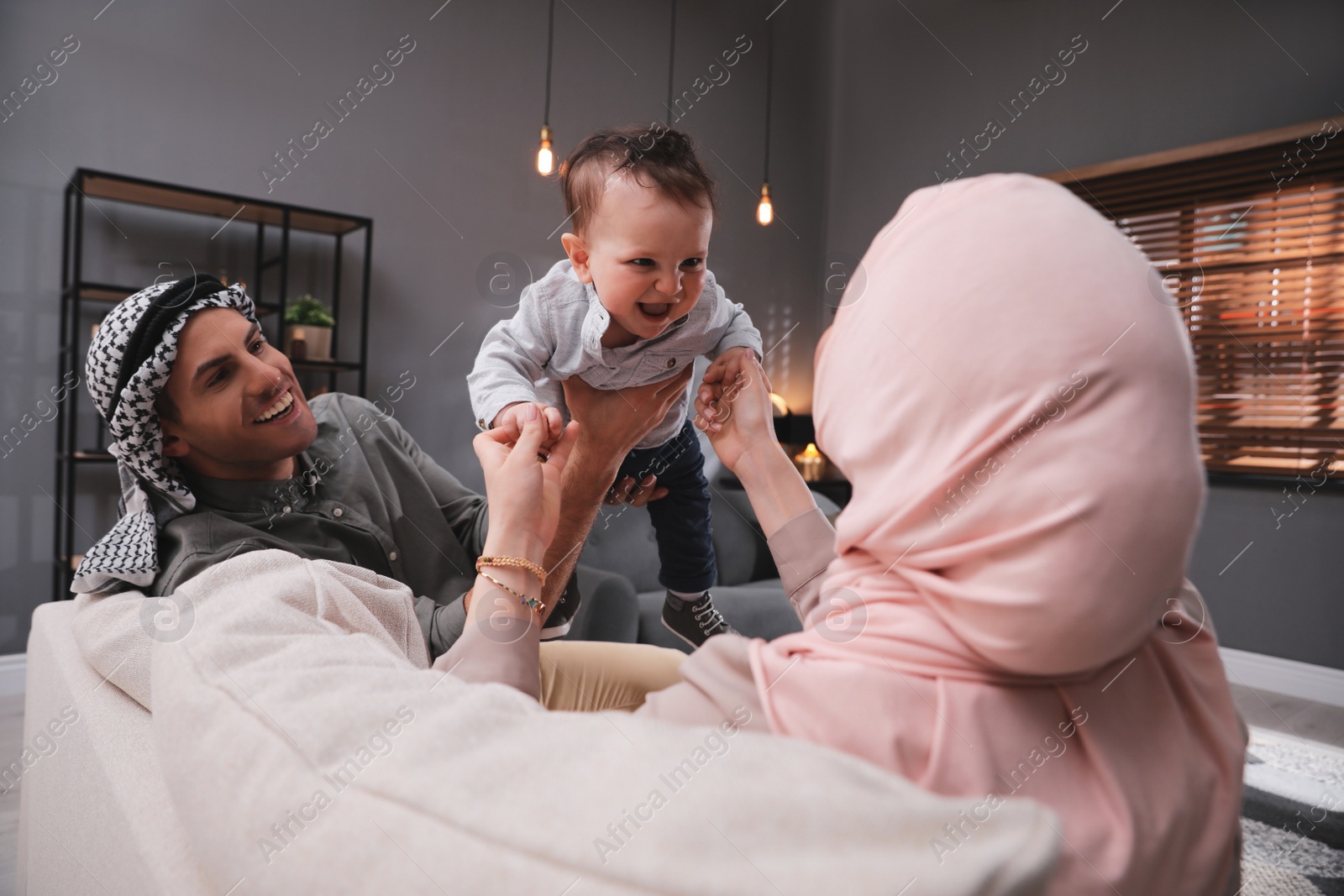 Photo of Happy Muslim family with little son in living room