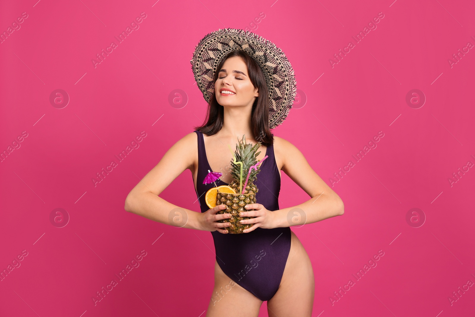 Photo of Beautiful woman in stylish swimsuit holding tropical cocktail on pink background