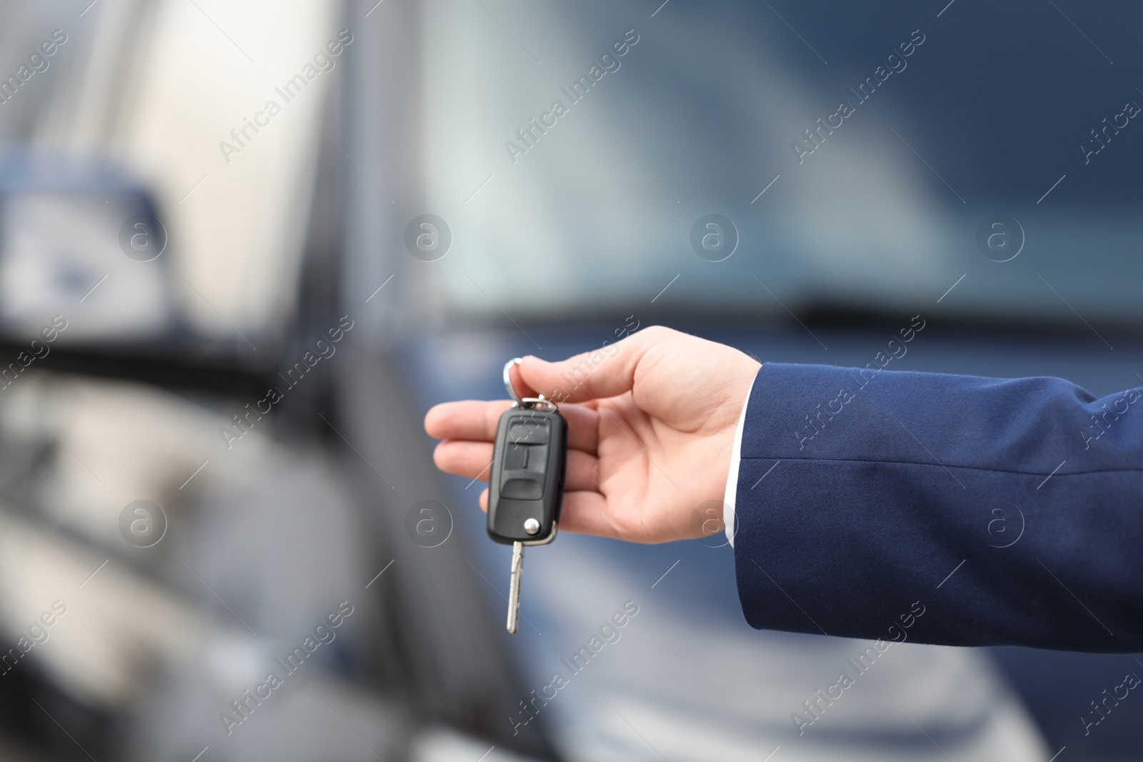 Photo of Man holding key in modern auto dealership, closeup. Buying new car