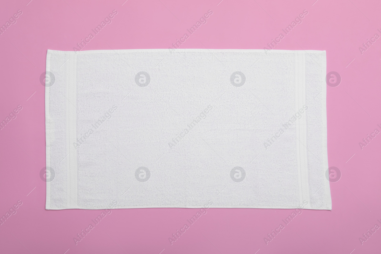 Photo of White beach towel on pink background, top view
