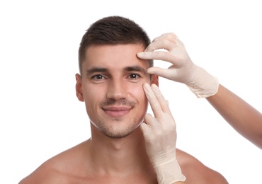 Photo of Doctor examining man's face for cosmetic surgery on white background