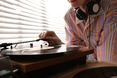 Photo of Young woman using turntable at home, closeup