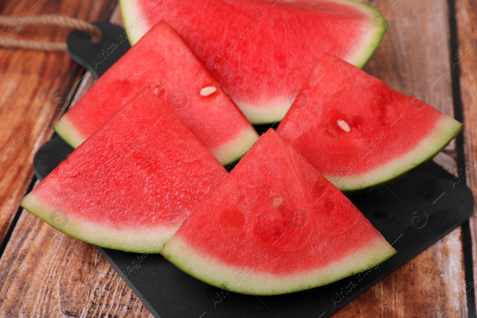 Photo of Pieces of juicy ripe watermelon on wooden table, closeup