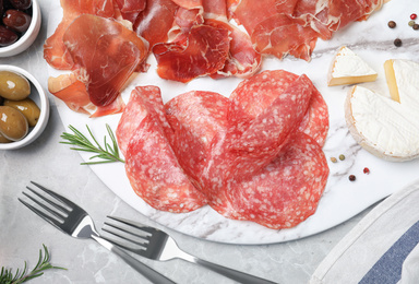 Photo of Tasty prosciutto served on light grey marble table, flat lay