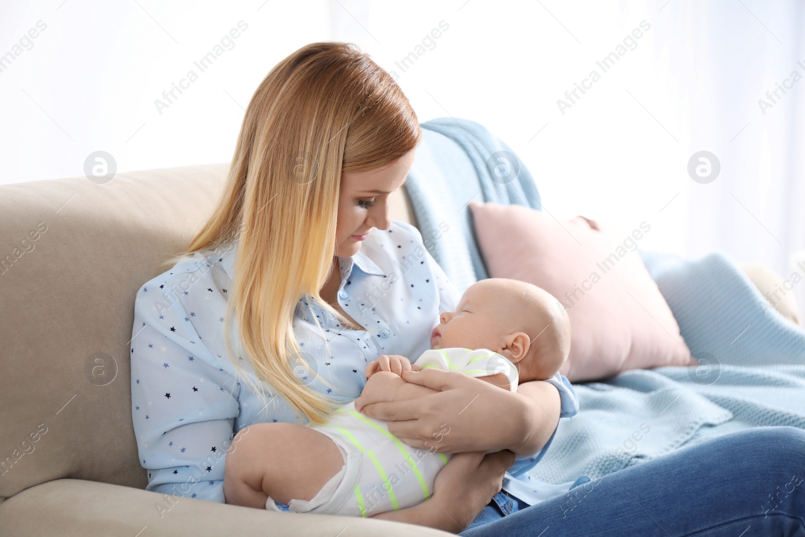 Photo of Mother with her little baby sitting in armchair at home