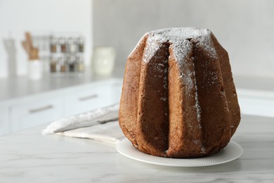 Delicious Pandoro cake decorated with powdered sugar on white table in kitchen, space for text. Traditional Italian pastry