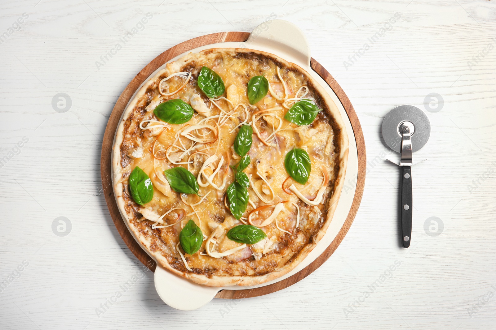 Photo of Delicious homemade pizza and cutter on wooden background, top view