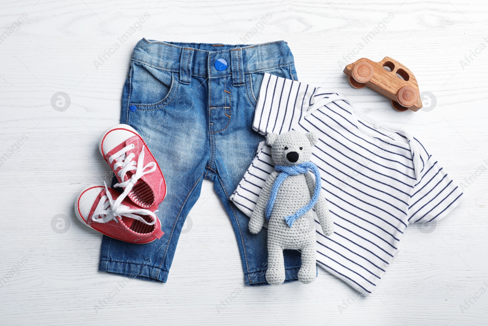 Photo of Flat lay composition with cute clothes on white wooden background. Baby accessories