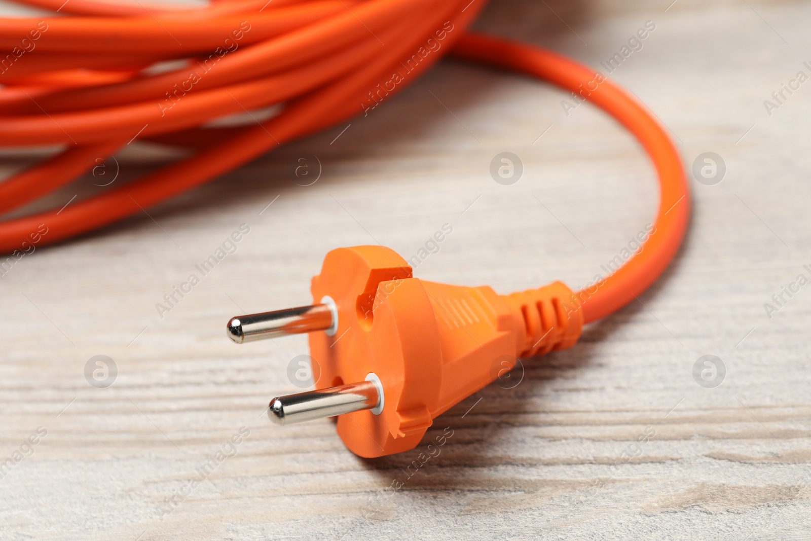 Photo of Extension cord on white wooden floor, closeup. Electrician's equipment