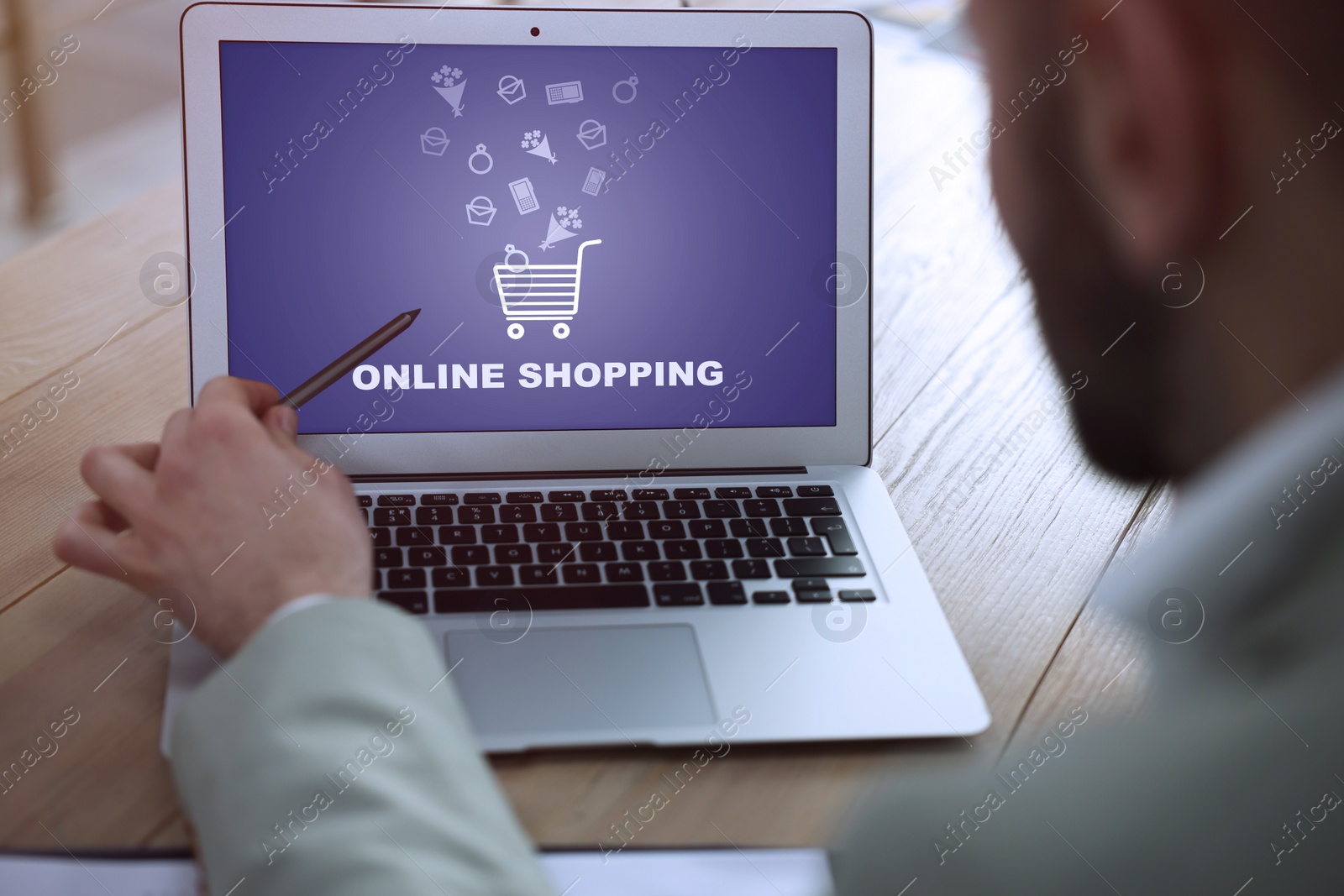 Image of Man using laptop for online shopping at wooden table, closeup