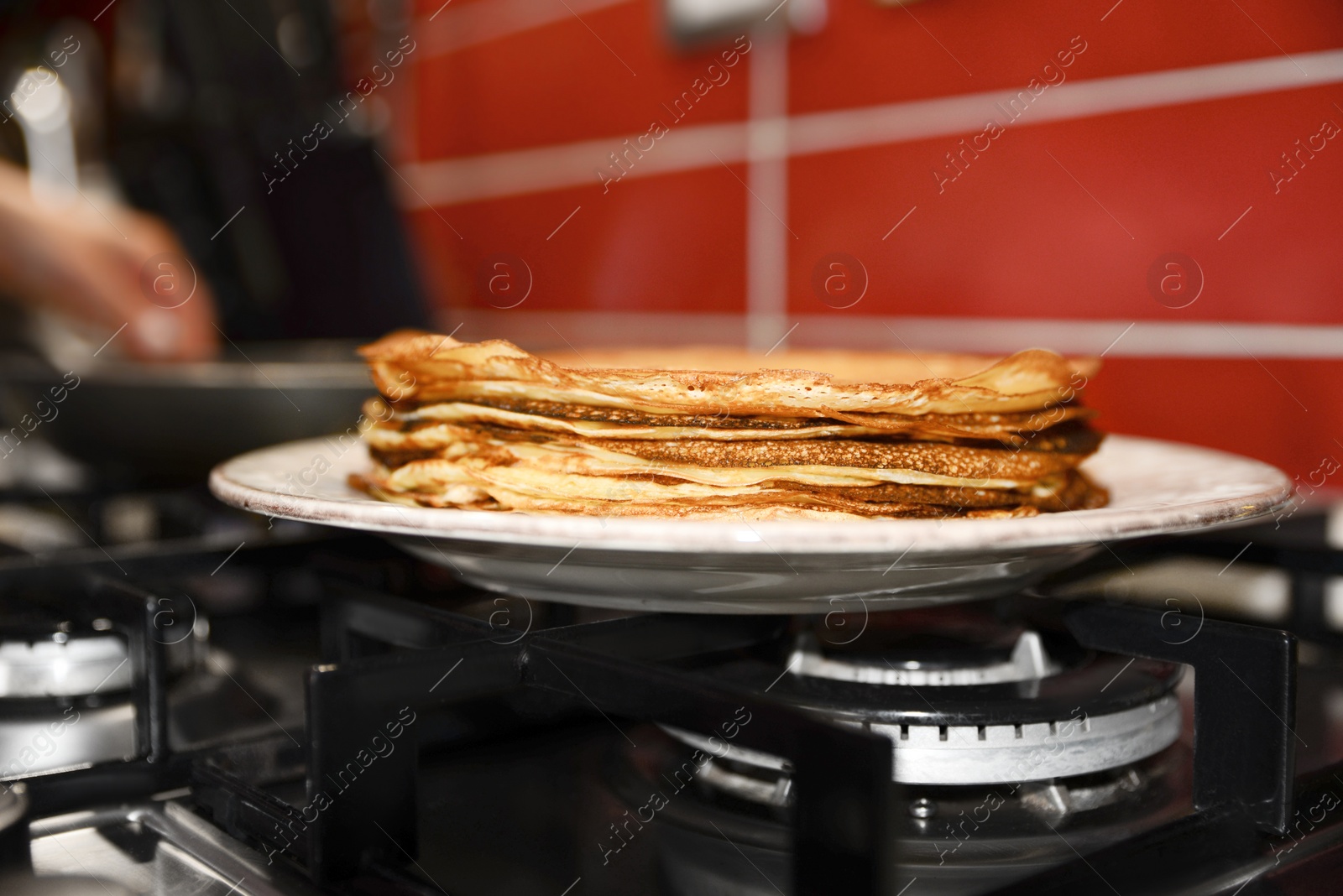 Photo of Plate of freshly made crepes on stove in kitchen, closeup