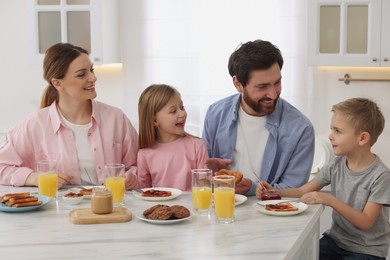 Photo of Happy family having breakfast at table in kitchen