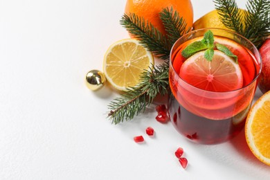 Photo of Christmas Sangria drink in glass, fir branches and fruits on white background, closeup. Space for text