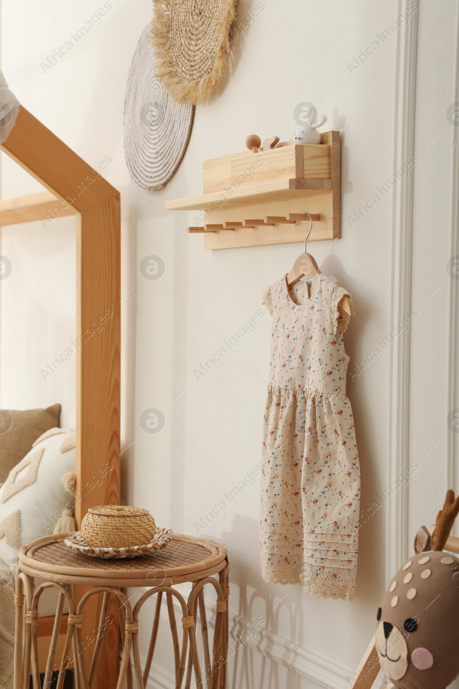 Photo of Wooden rack with cute dress in child room. Interior design