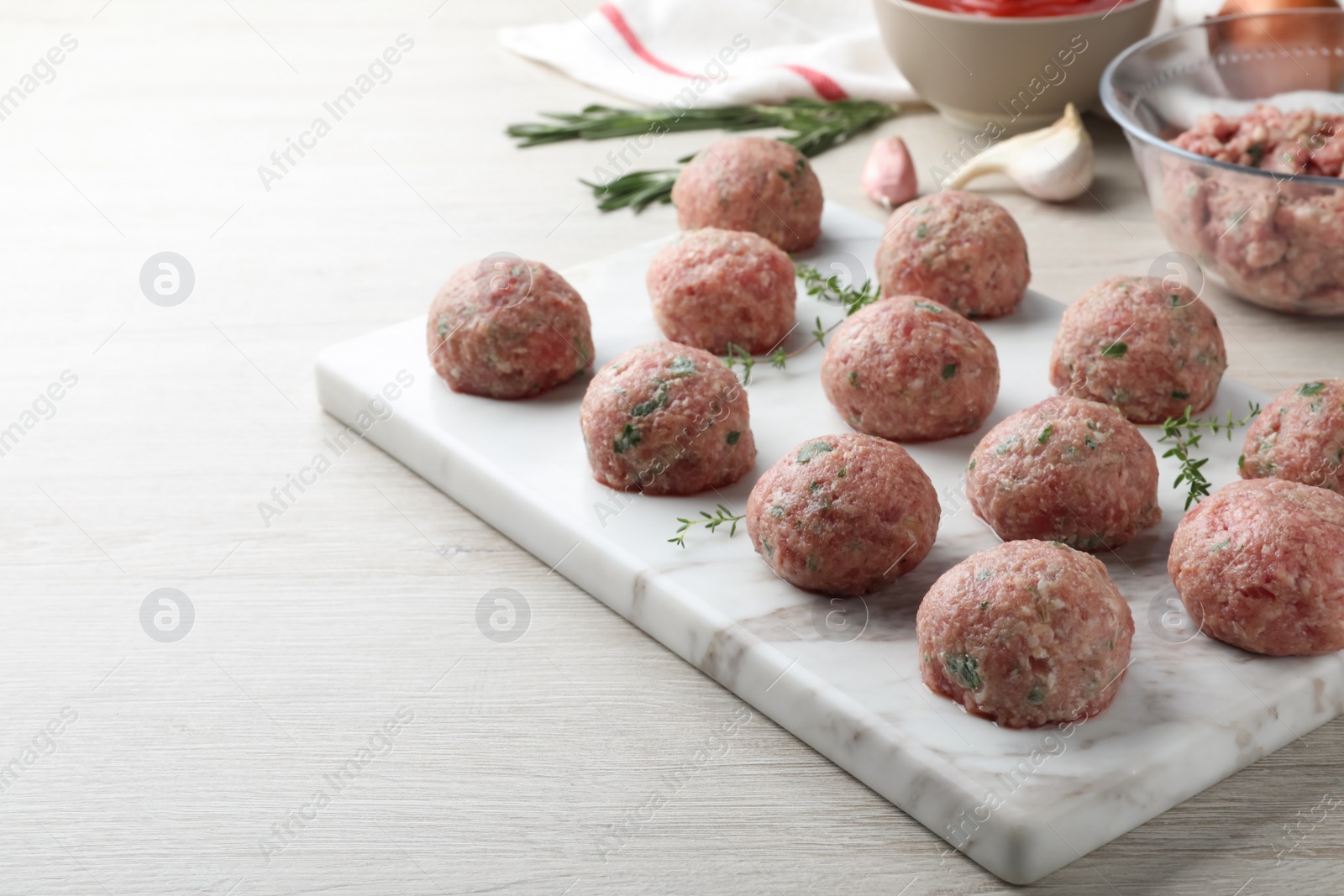 Photo of Many fresh raw meatballs on white wooden table, space for text